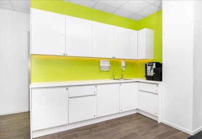 Modern kitchen and breakout area with white cabinetry and a vibrant lime green backsplash.