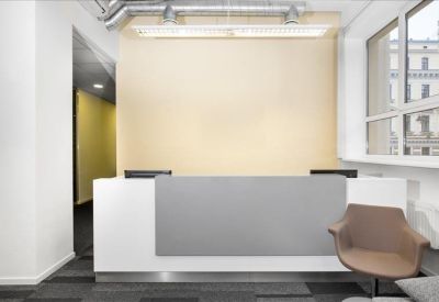 Sleek white and grey reception desk in a well-lit entrance lobby with large windows.