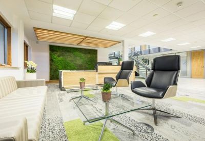 Bright reception area featuring a green moss feature wall and stylish black armchairs.