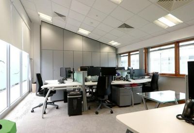 Open-plan office space with modern workstations, ergonomic chairs, and large windows.