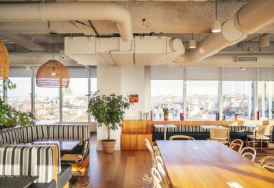 Long wooden communal table in a sunlit dining area with industrial ceiling details.