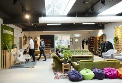 Vibrant lounge area featuring green sofas, colorful bean bags, and a living moss wall with signage.