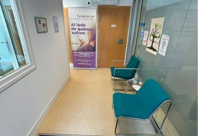 Reception area with teal armchairs and a glass partition.
