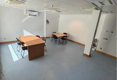 Spacious open room with multiple wooden work tables and overhead lighting.