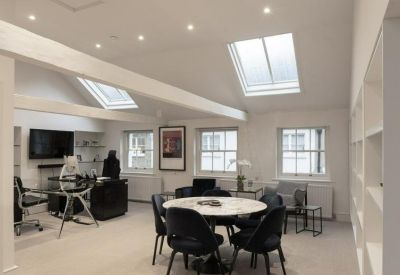 Bright office space with sloped ceilings, skylights, and a round marble meeting table.