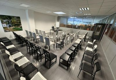 Large conference room with rows of chairs facing a central desk.