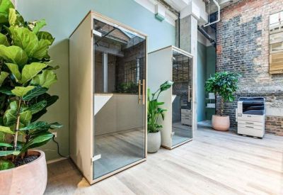 Minimalist phone booths for private calls surrounded by indoor greenery and warm wood floors.