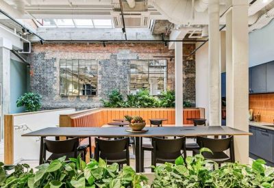 Comfortable lounge area featuring built-in orange seating, lush plants, and brick walls.