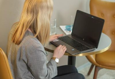 Close-up of a professional working at a bistro table with a laptop.