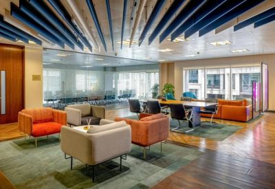 Spacious communal lounge featuring colorful armchairs and blue acoustic ceiling panels.