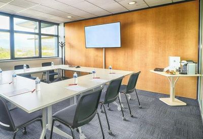 Professional meeting room featuring a U-shaped table and wall-mounted television.