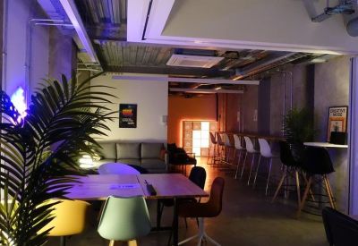 Breakout area with colourful chairs, ambient lighting, and a feature neon sign.