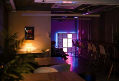 Modern lounge area with neon wall art and high stools near a lit backdrop.