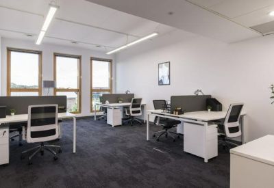 Four-person office suite with white desks, ergonomic chairs, and large windows.