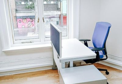 Single workstation with white desk and blue task chair next to a large window.