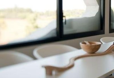 Bright breakout space with a long wooden counter and panoramic windows overlooking greenery.