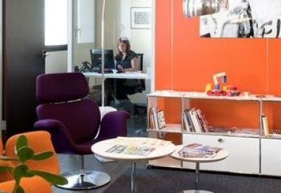 Colorful lounge area featuring orange and purple armchairs against a bright orange accent wall.