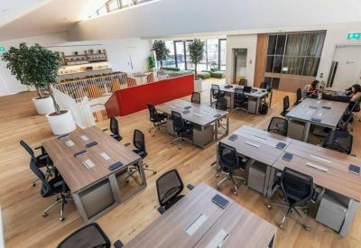 Bright open-plan workspace with wooden floors and several large desks.