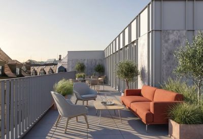 Sunlit rooftop terrace with orange sofa, gray armchairs, and potted plants.