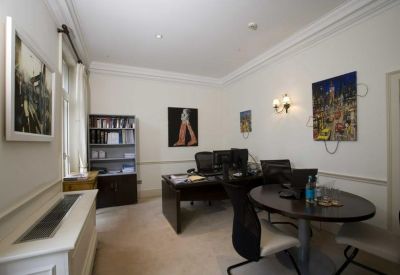Private office suite with dark wood desks and modern artwork on white walls.