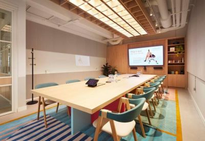 Professional meeting room with a long wooden table, teal chairs, and a large presentation screen.
