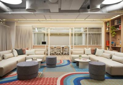 Large breakout area featuring curved sofas and colourful patterned rugs.