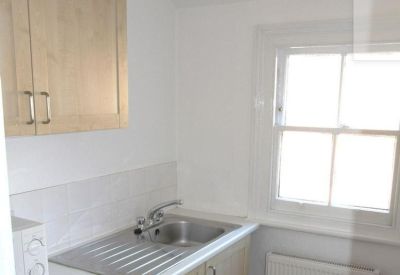 Compact communal kitchen area with light wood cabinets and a stainless steel sink.