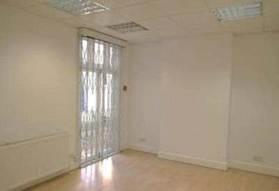 Empty private office with natural light, wood flooring, and white walls.
