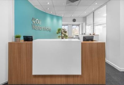 Branded reception desk with a wood-panel base and vibrant teal curved wall.