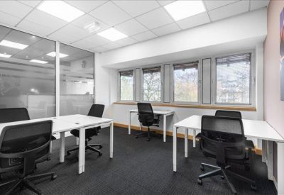 Bright four-person office suite with white desks and glass partitions.