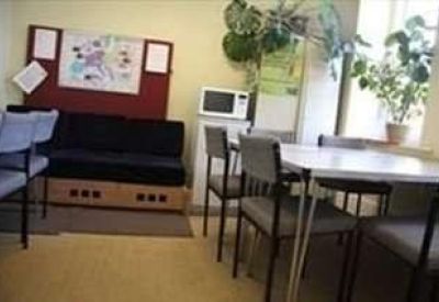 Communal break area with a sofa, dining table, microwave, and potted plants.