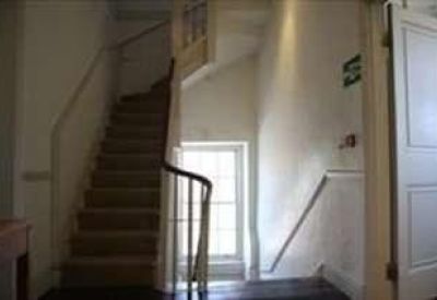 Bright carpeted staircase with a classic wooden banister and white walls.