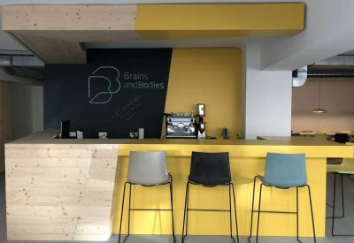Communal cafe area with a yellow counter, wooden accents, and modern bar stools.