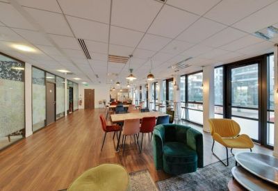 Spacious communal lounge with colorful armchairs, wooden flooring, and large windows.