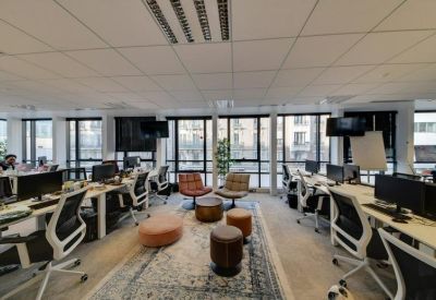 Bright open-plan office with multiple workstations and a central lounge area on a vintage rug.