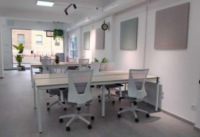 Modern open-plan office with quad desk setup and minimalist design.