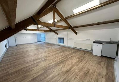 Open attic workspace with a small kitchenette unit and skylights set into a vaulted beamed ceiling.
