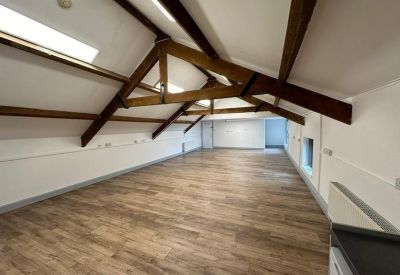 Bright, empty open-plan office showing a long perspective of the wood-beamed attic space.
