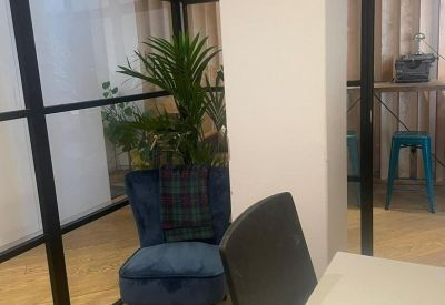 Blue velvet armchair with a plaid cushion in a bright breakout area.