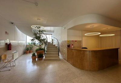 Reception area with a wooden desk, a winding staircase, and indoor greenery.
