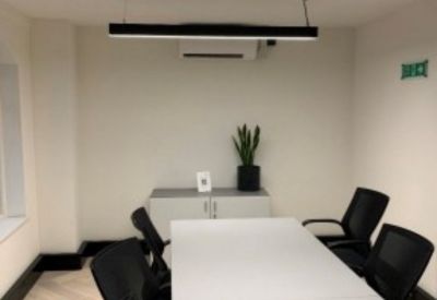 Bright meeting room with white table, black chairs, and a potted plant.