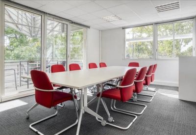 Large meeting room with red chairs and floor-to-ceiling windows leading to a balcony.