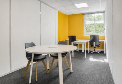 Modern breakout room with a yellow accent wall and a round white meeting table.