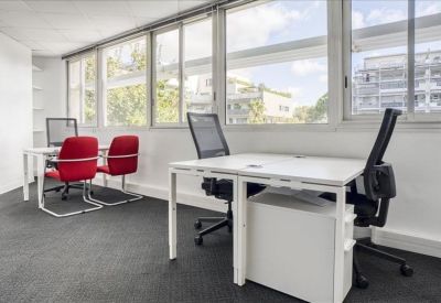 Bright office space with white desks, ergonomic black chairs, and red side chairs.
