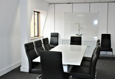Modern meeting room featuring a long white table and sleek black high-back chairs.