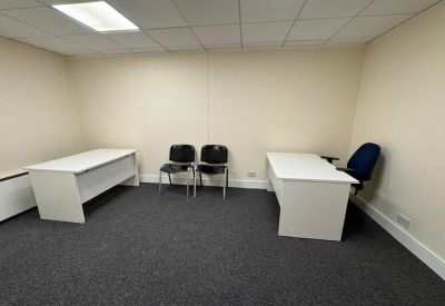 Small private office suite with two desks and charcoal grey carpeting.