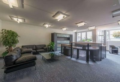 Spacious lounge area with dark leather sofas, a glass coffee table, and large windows.