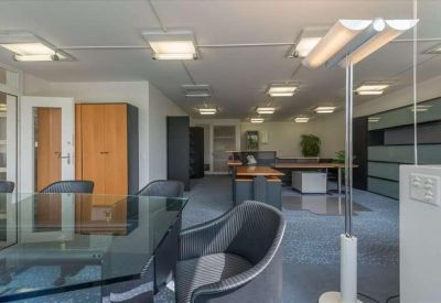 Open office area featuring a glass meeting table and several workstations in the background.