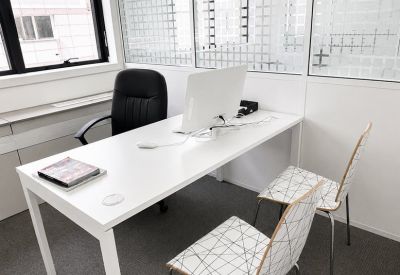 Private office suite with a white desk, executive chair, and two patterned guest chairs.
