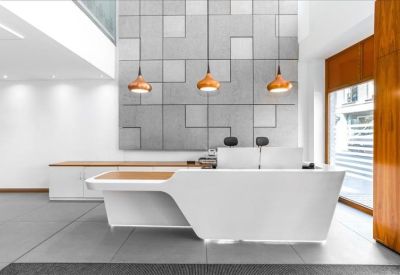 Sleek white reception desk with modern copper pendant lights and a textured feature wall.